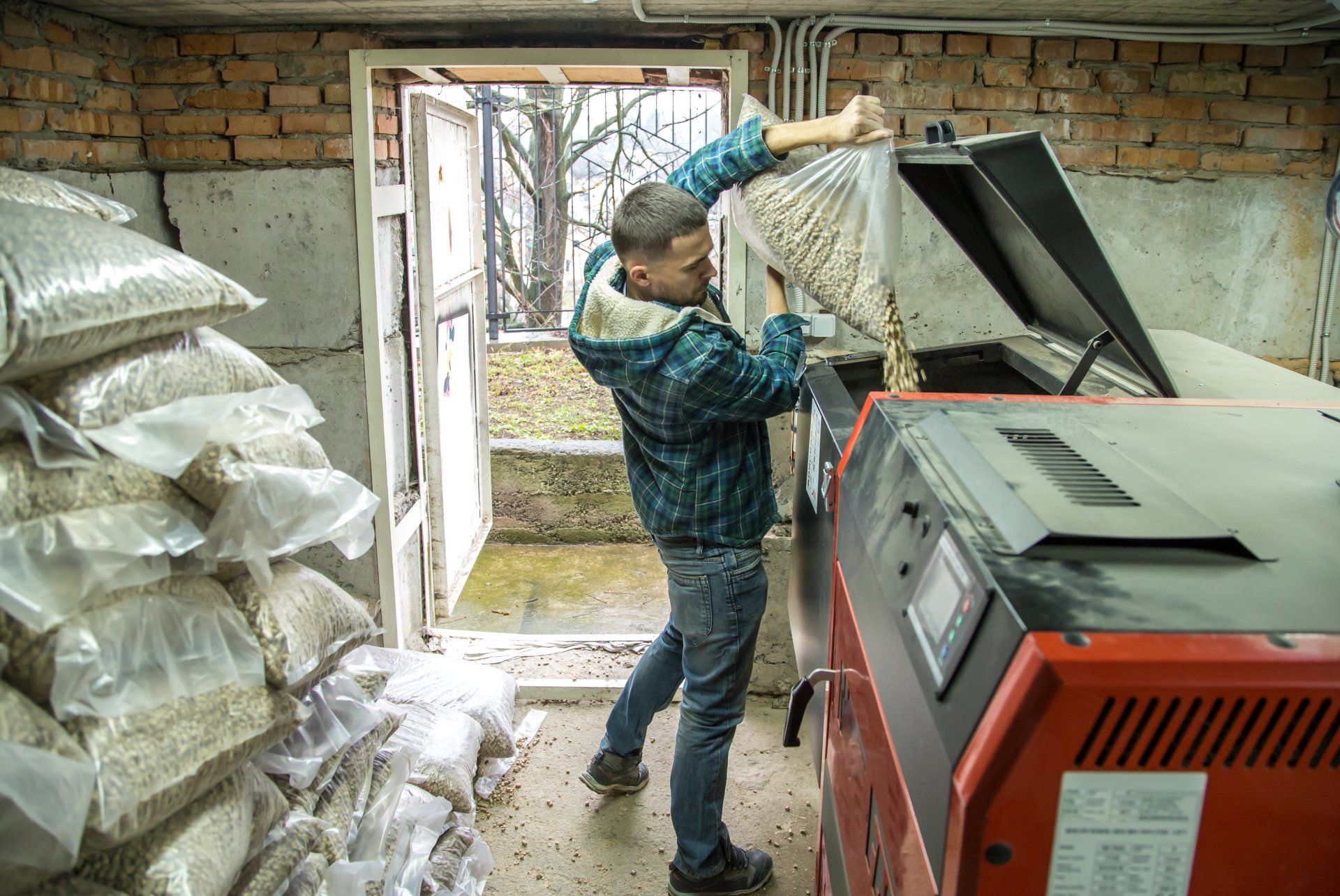 A man dumping a bag of pellets into the hopper.
