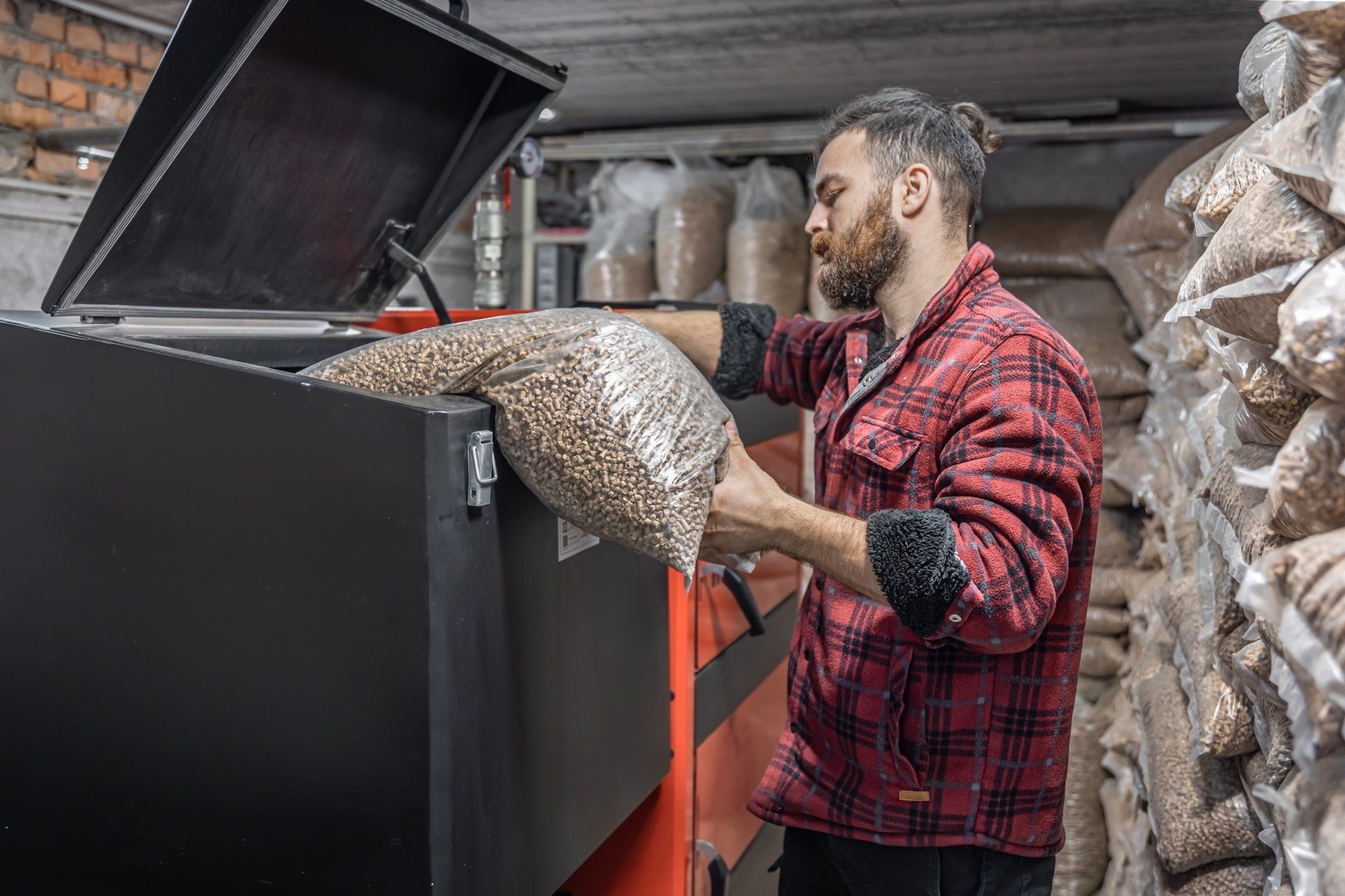 A man loading hardwood pellets into the hopper of wood pellet stove.