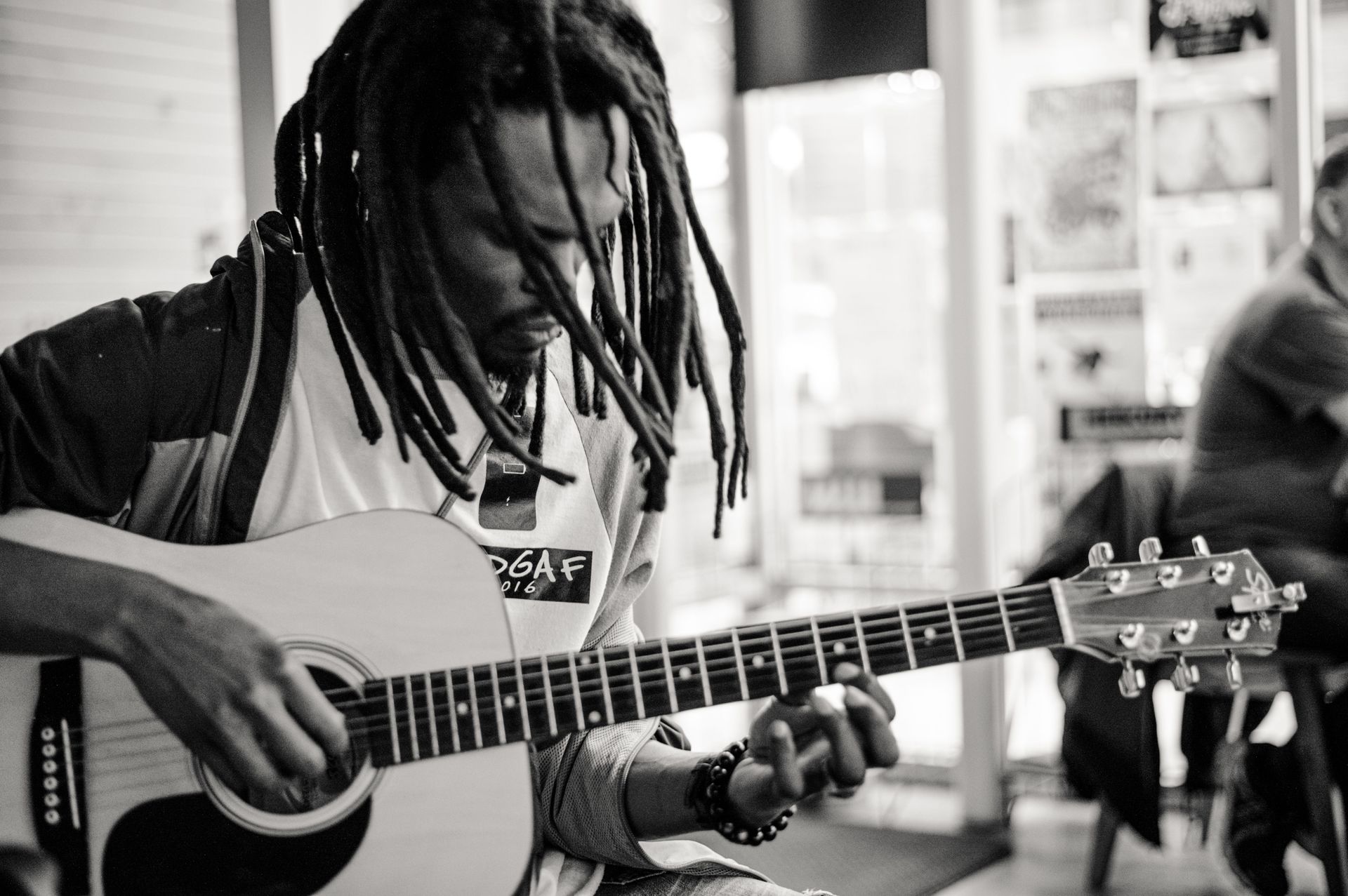 Person playing an acoustic guitar indoors in black and white