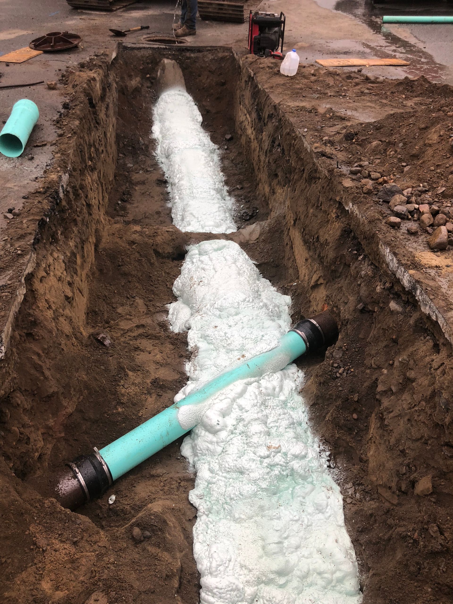 A pipe is being insulated and installed in a hole in the ground.