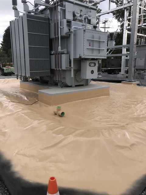 A large transformer is sitting on top of a concrete surface, with a protective covering on the concrete