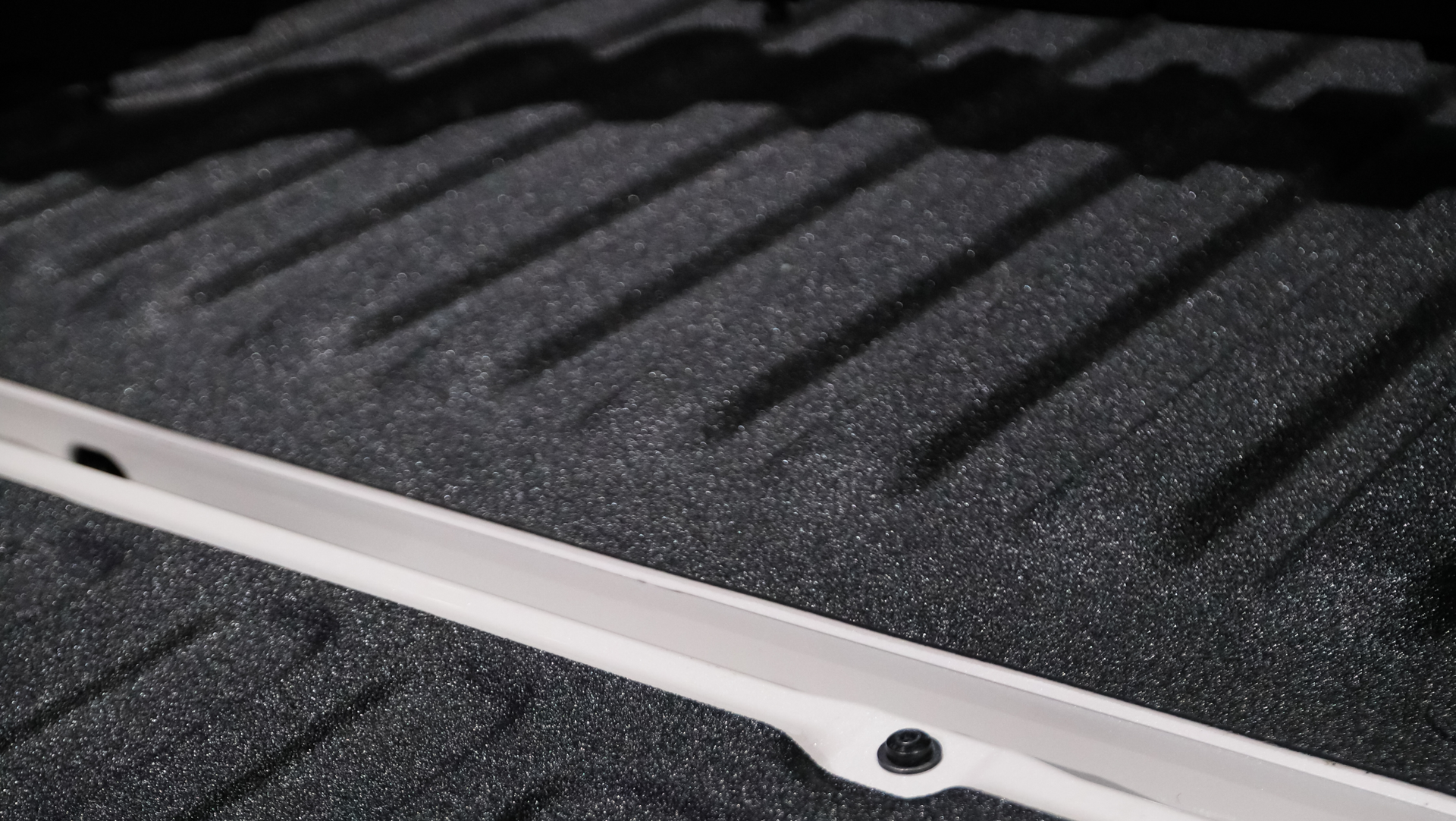 A close up of a truck bed spray on bedliner with a white stripe on it.