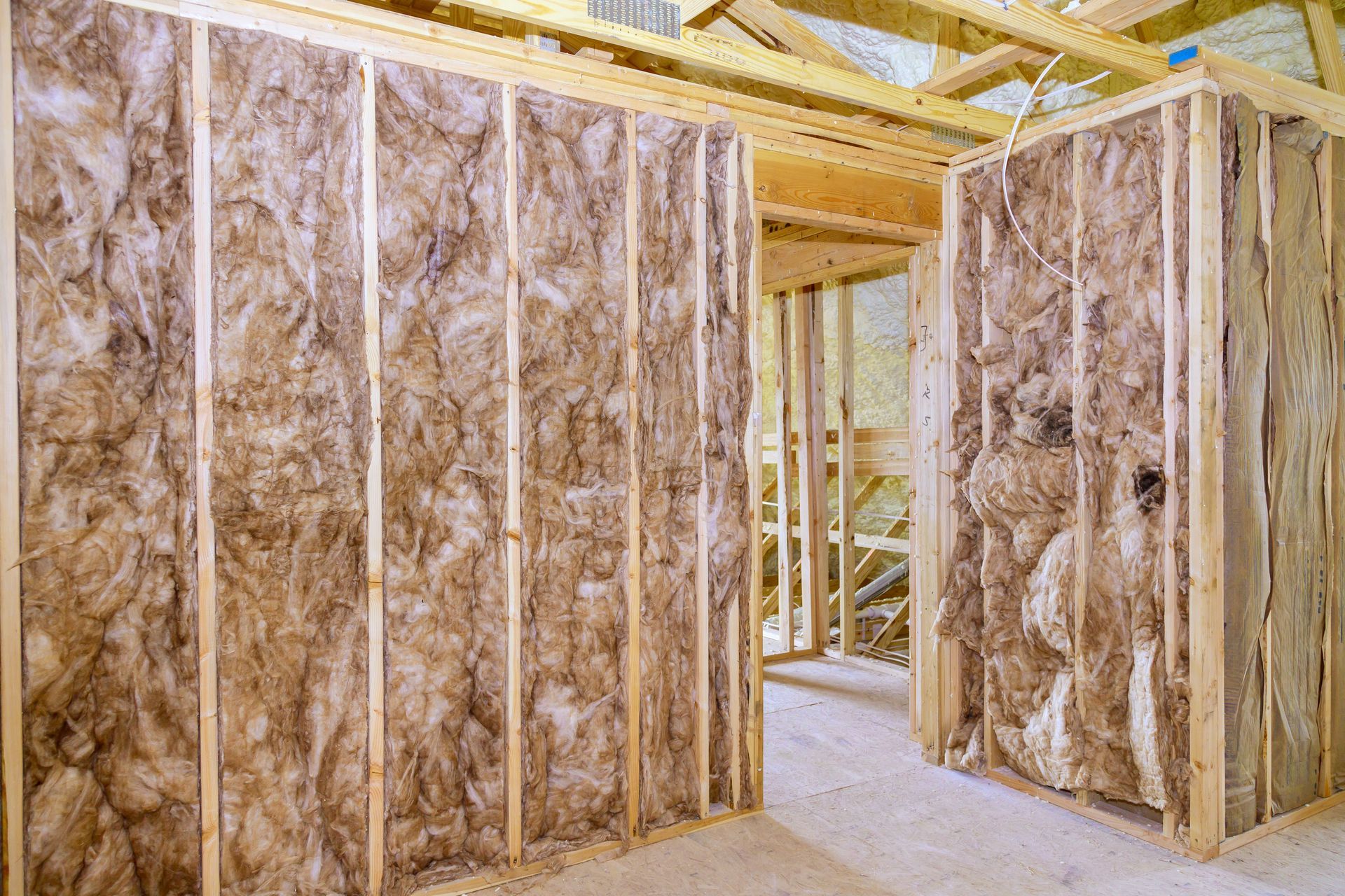 A room with wooden beams and a ceiling that is covered in spray foam.
