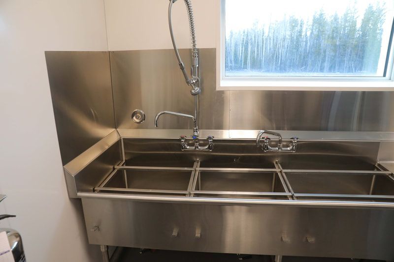 A stainless steel kitchen sink with three sinks and a window.