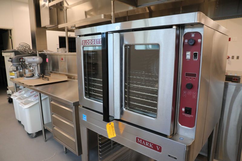 A stainless steel oven is sitting on a shelf in a kitchen.