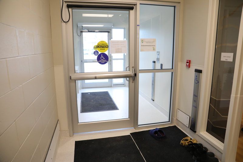 A hallway with a glass door and a mat on the floor