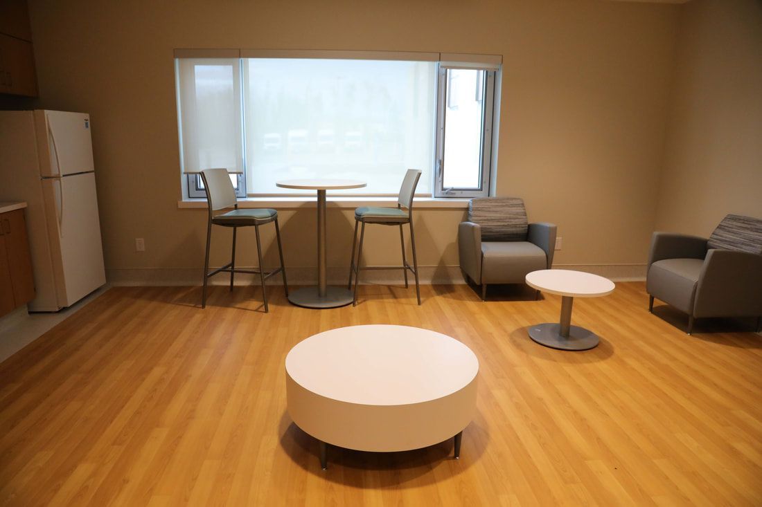 A living room with a table , chairs , and a window.