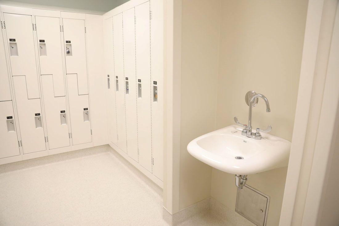 A locker room with white lockers and a sink.
