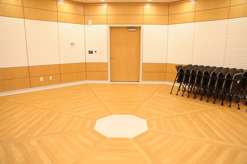 A room with a wooden floor and chairs lined up in a circle.