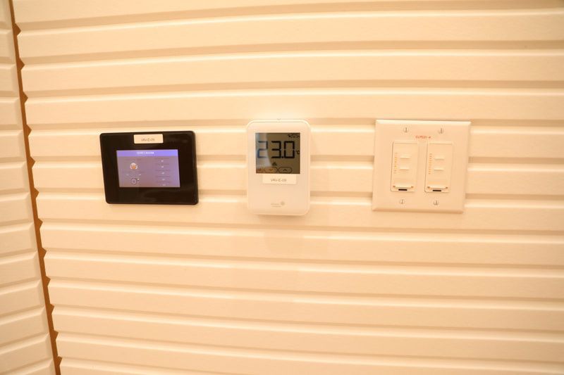 A wall with a thermostat and a clock on it.