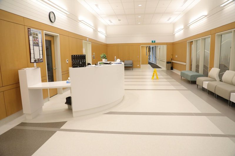 There is a yellow caution wet floor in the lobby of a hospital.