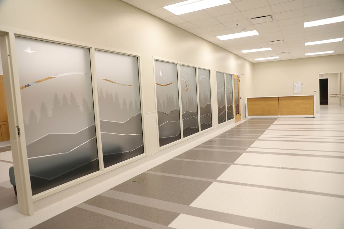 A long hallway with a lot of windows and paintings on the wall.