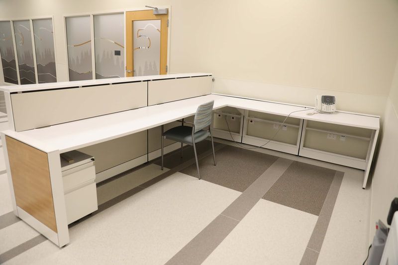 A cubicle with a desk and a chair in a room.
