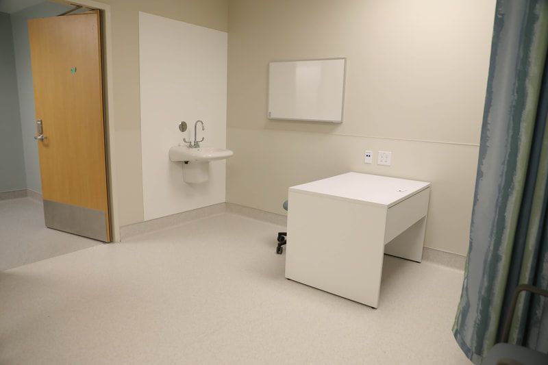 A hospital room with a sink and a whiteboard on the wall.