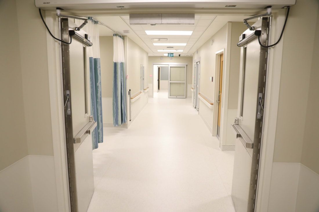 An empty hospital hallway with two doors open.