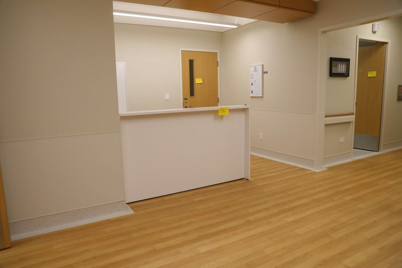 An empty room with a wooden floor and a white counter.