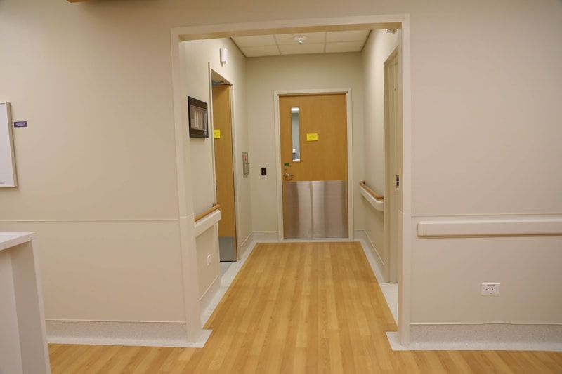 A hospital hallway with wooden floors and a door