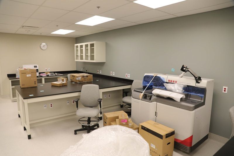 A laboratory with a desk , chair , boxes and a machine.