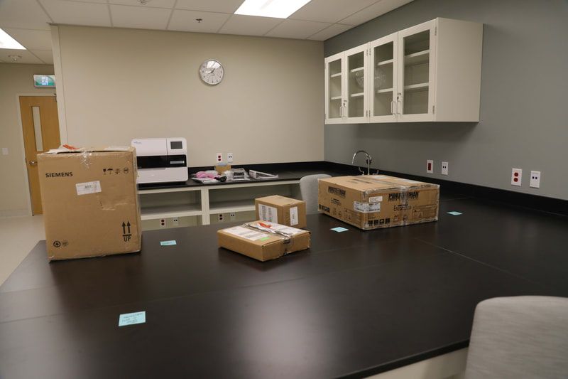 A lab with boxes on the counter and a clock on the wall.