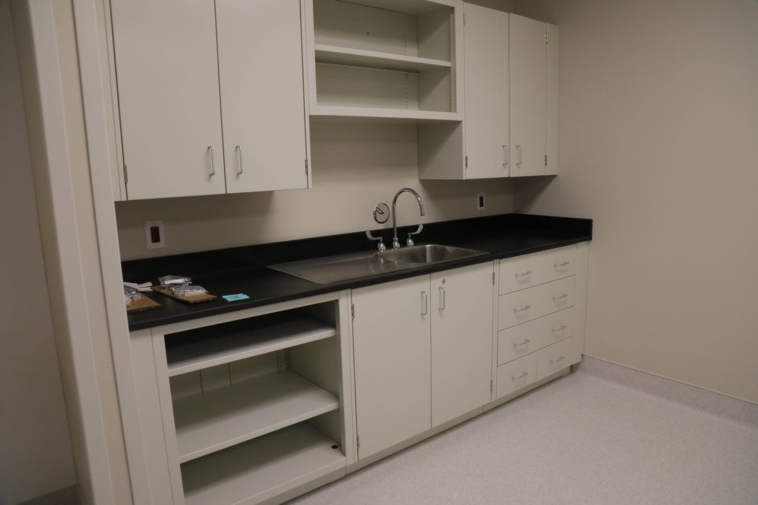 A kitchen with white cabinets , black counter tops , and a sink.