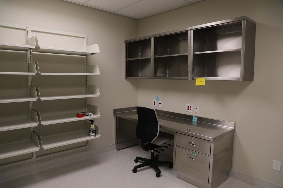 An empty room with a desk , chair and shelves.