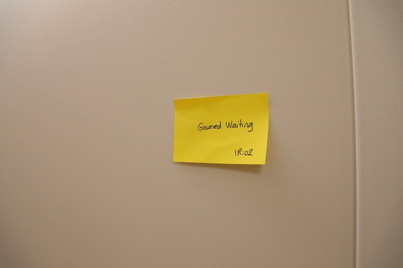 A yellow sticky note on a wall that says good waiting