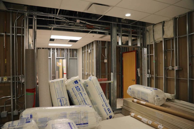 A room under construction with a lot of rolls of insulation on the floor.