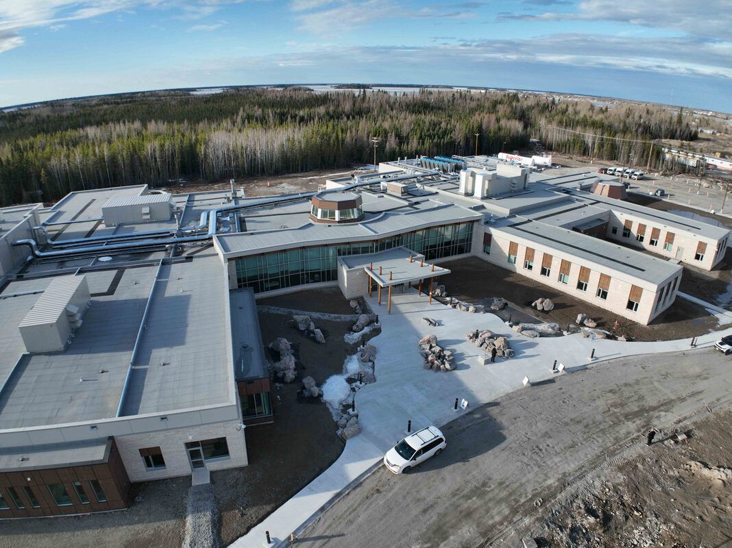 An aerial view of a large building with a lot of windows surrounded by trees.