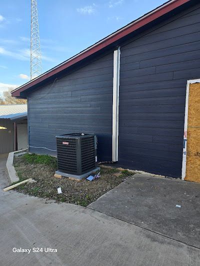 A blue building with a black air conditioner on the side of it.