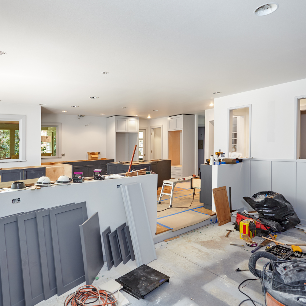 Kitchen undergoing renovation; gray cabinets, tools, and materials strewn about. Interior view, construction zone.