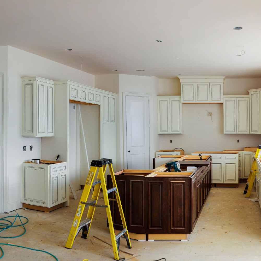 Kitchen under construction, cream cabinets, dark brown island, yellow ladder.