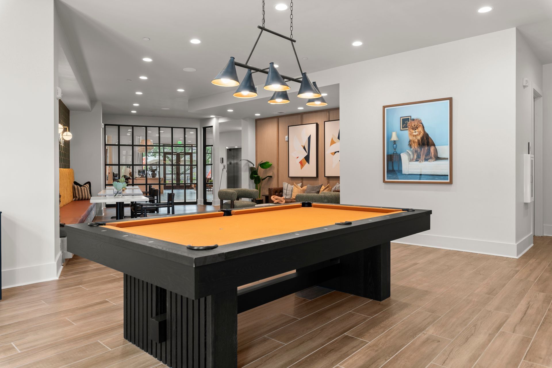 Pool table in a room with a painting of a dog. Modern decor with a view of a seating area.