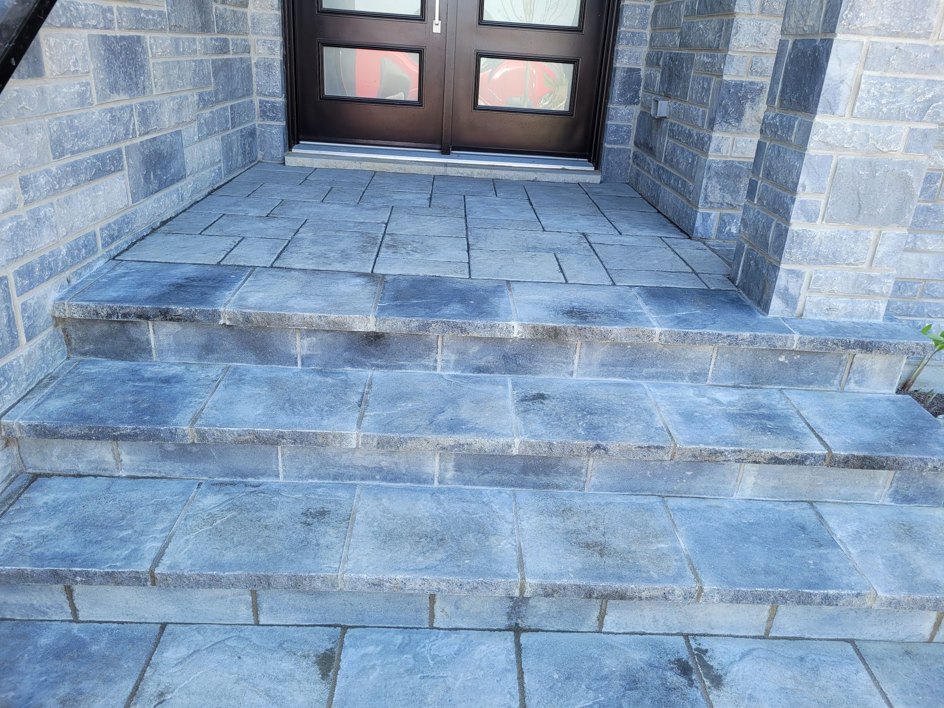 Stone steps leading to a dark front door with stone veneer walls.