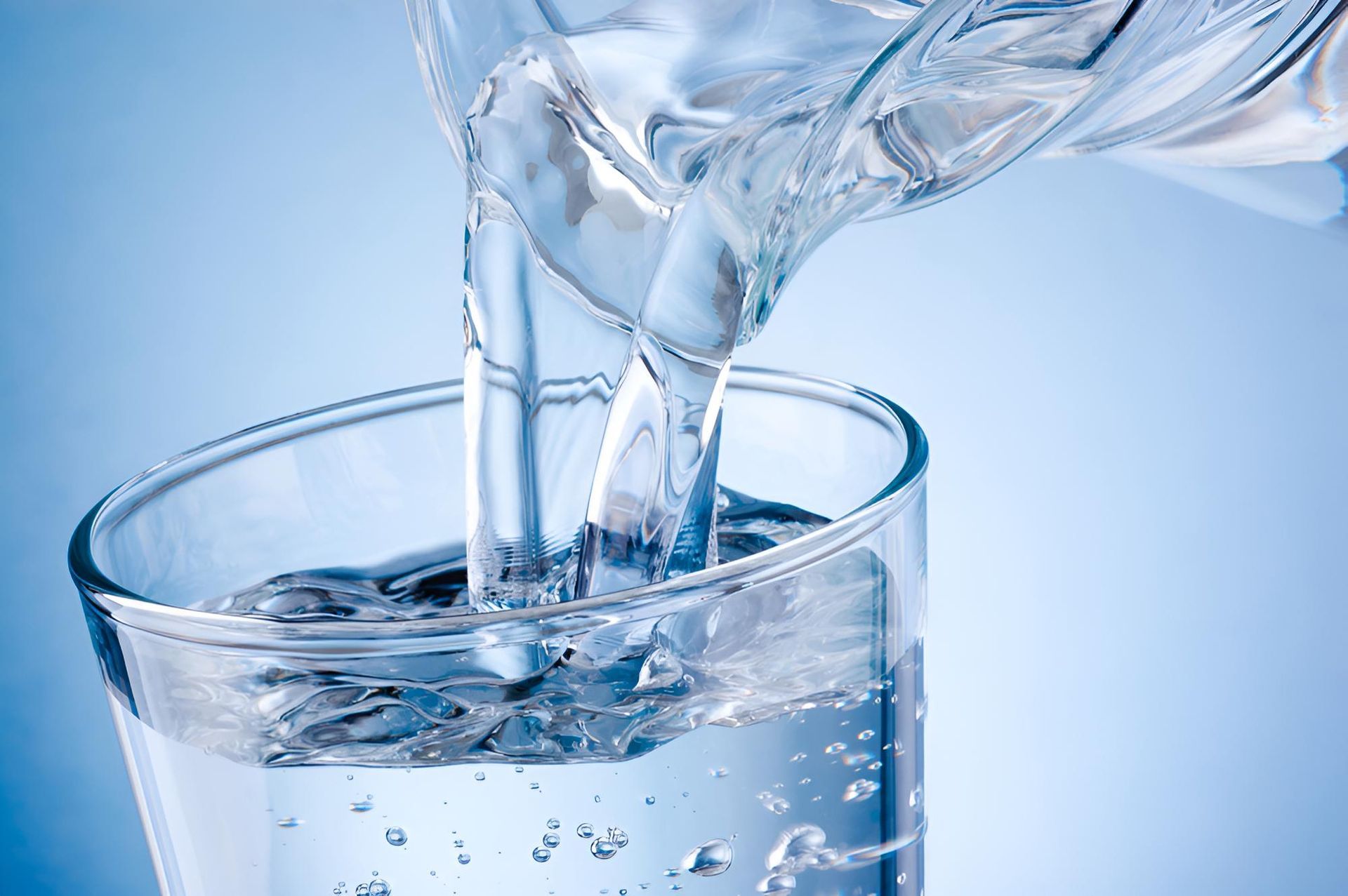 Water Is Being Poured Into A Glass On A Blue Background — Porta-Vac in Bowen, QLD