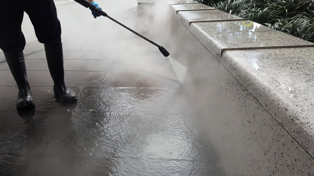 A Person Is Using A High Pressure Washer To Clean A Sidewalk — Porta-Vac in Cannonvale, QLD