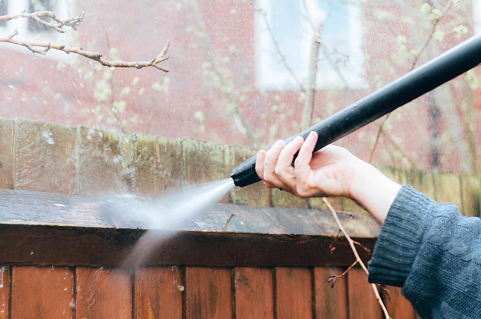 A Person is Using a High Pressure Washer to Clean a Wooden Fence High-Pressure Cleaning Cannonvale