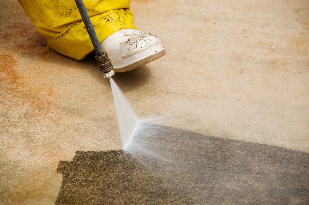 Maintenance Worker Cleaning Old Dirty Driveway With A Pressure Cleaner — Porta-Vac in Proserpine, QLD