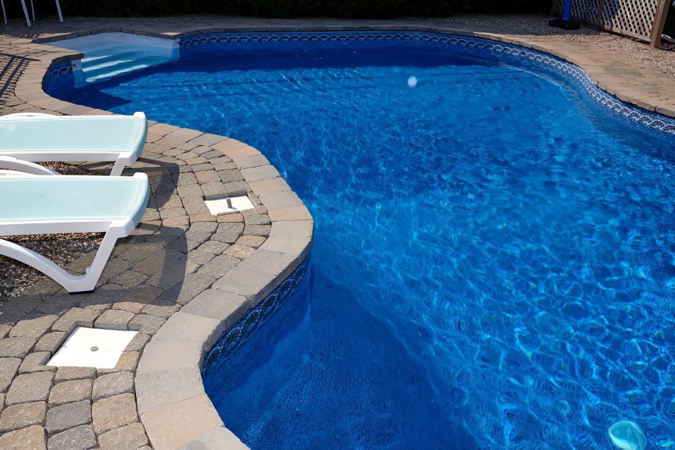 A Large Swimming Pool With Two Lounge Chairs In The Water — Porta-Vac in Bowen, QLD