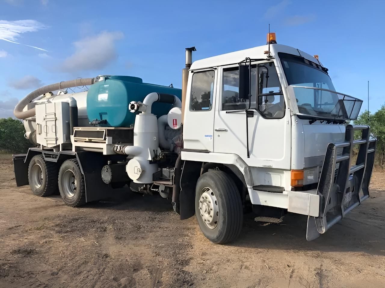 A White Vacuum Truck is Parked in a Dirt Field — Porta-Vac in Bowen, QLD