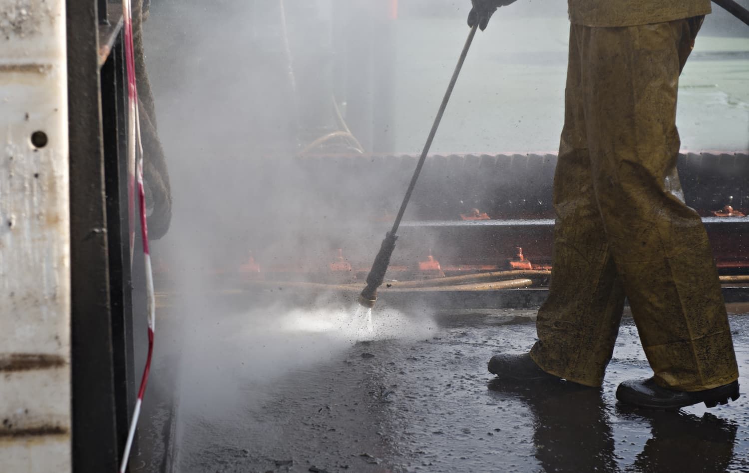 A Man Is Using A High Pressure Washer To Clean The Ground — Porta-Vac in Proserpine, QLD