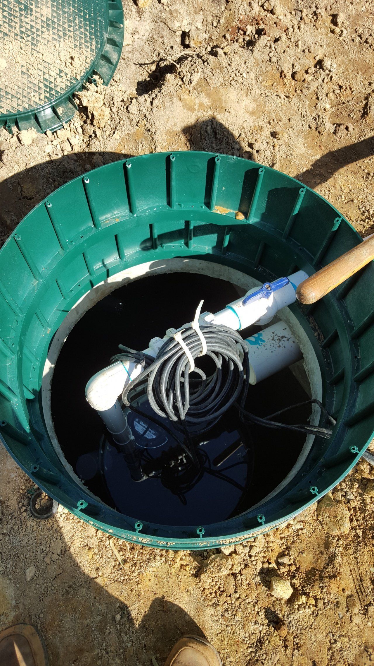 Green septic tank with a white and black apparatus inside, visible from above.