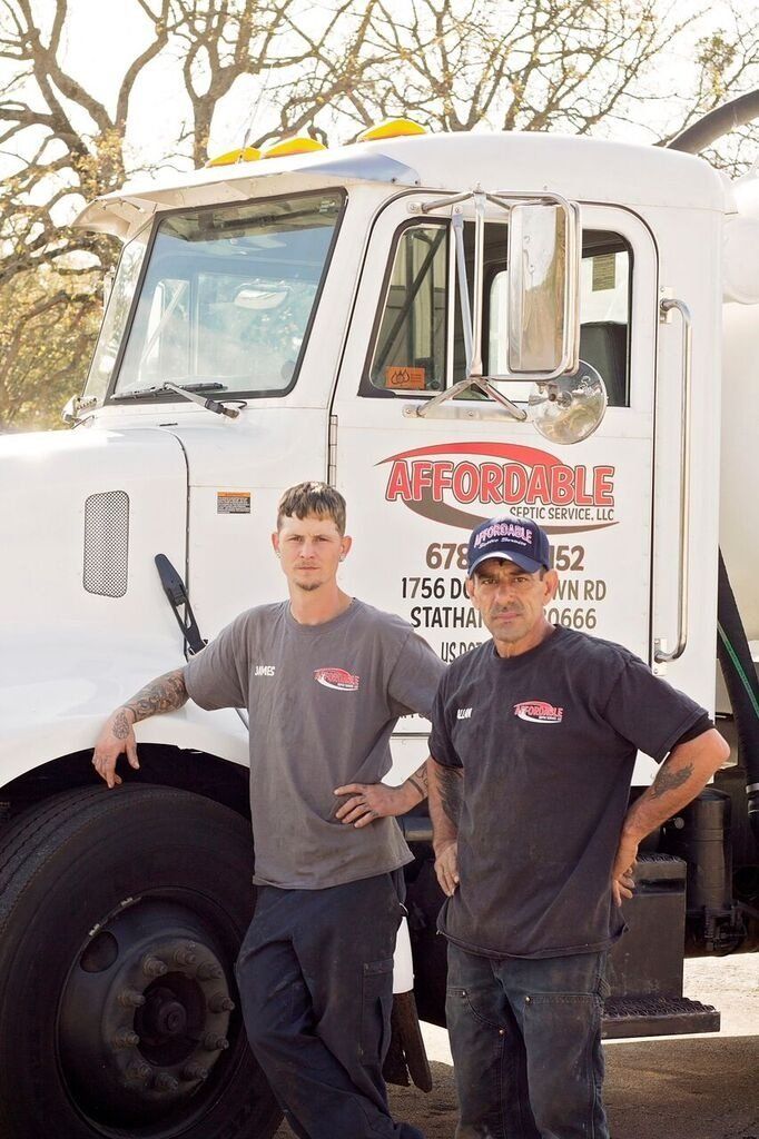 Two men stand next to a white truck with business logo.