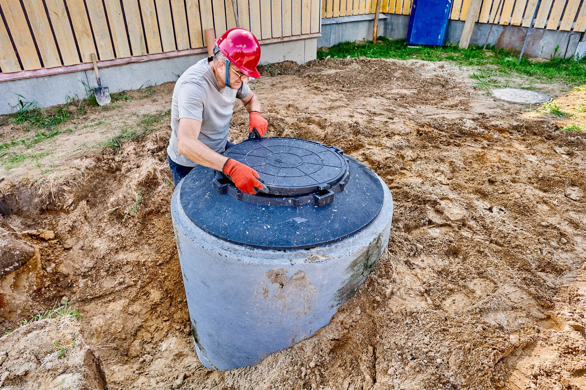 A man inspecting the manhole cover on a concrete septic tank.