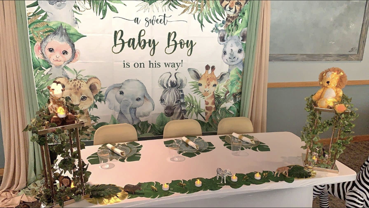 Baby shower with jungle theme decorations: backdrop, table settings, and plush toy.