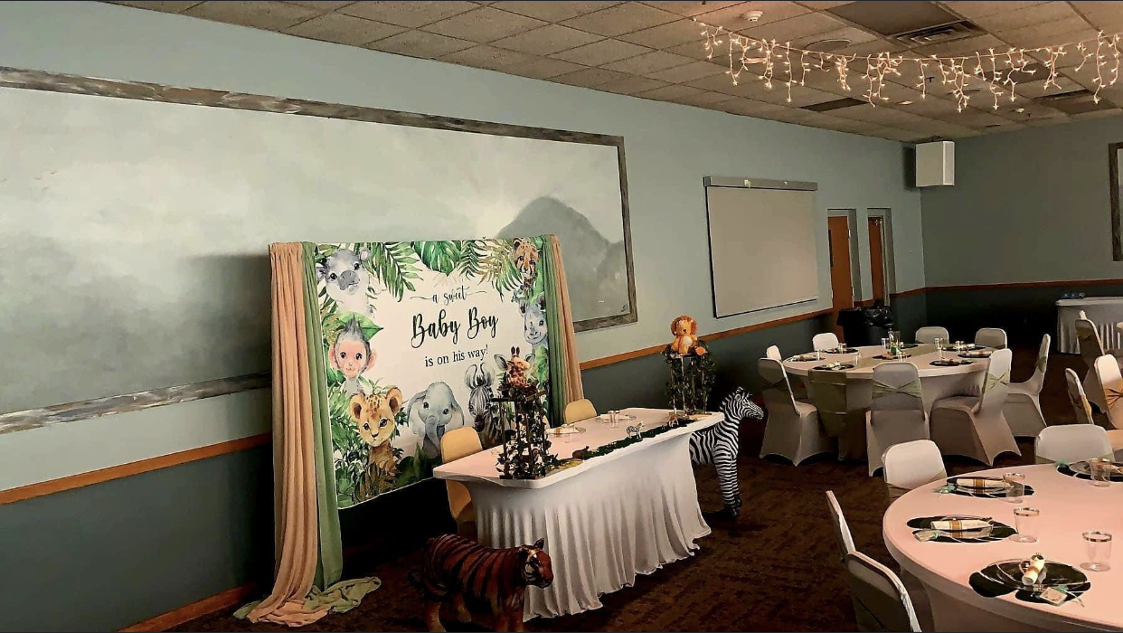 Event space decorated with animal-themed decorations. Tables are set, and a sign says 