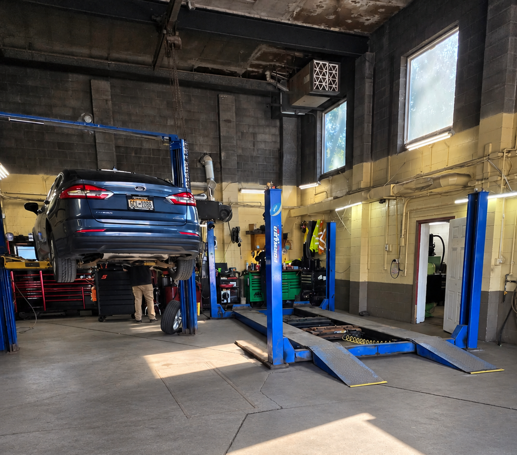 Blue car on a lift in an auto repair shop with ramps and service bays