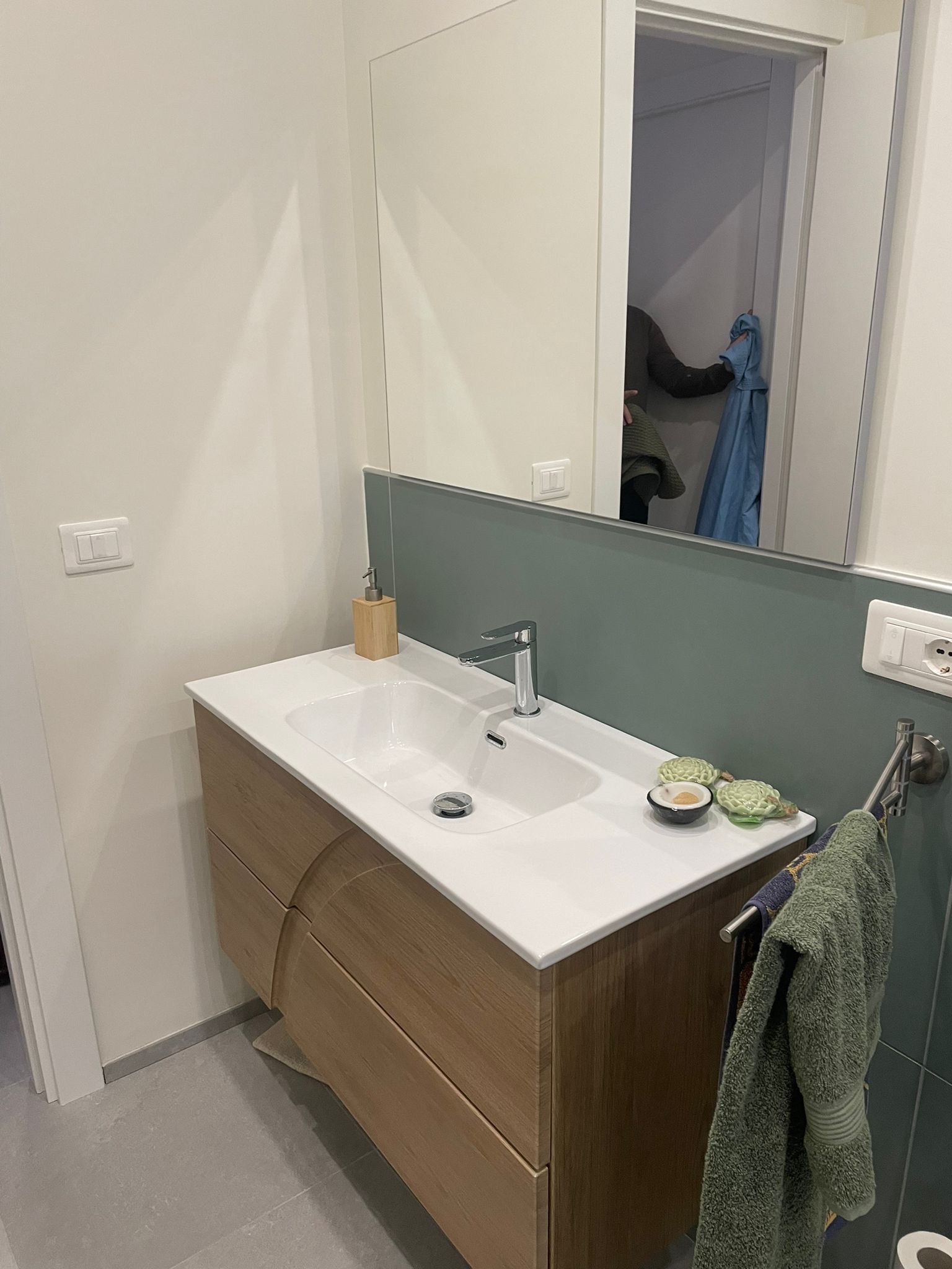 Un bagno con lavandino, specchio e portasciugamani.