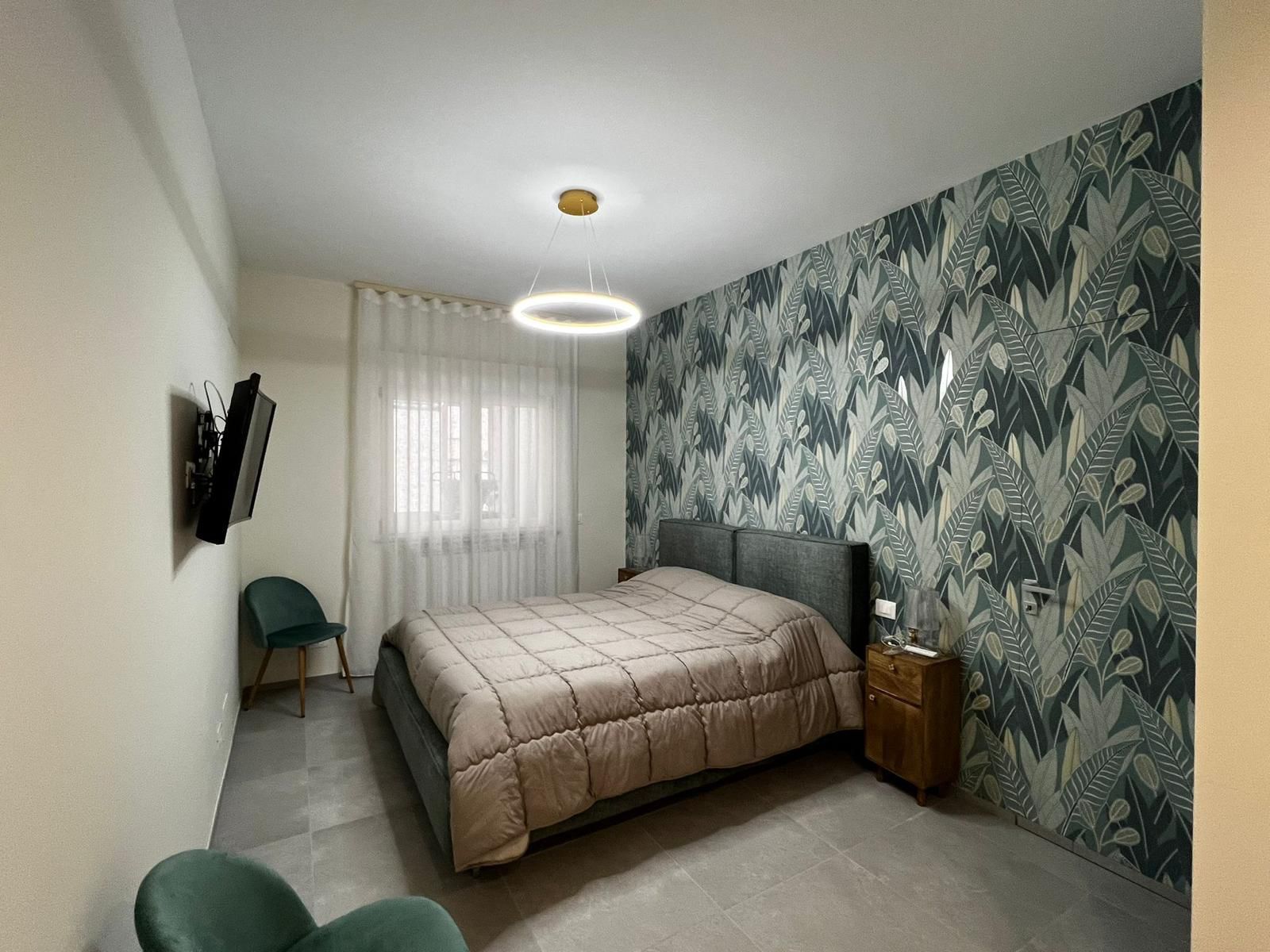 Una camera da letto con un letto, un comodino, una sedia e una televisione.