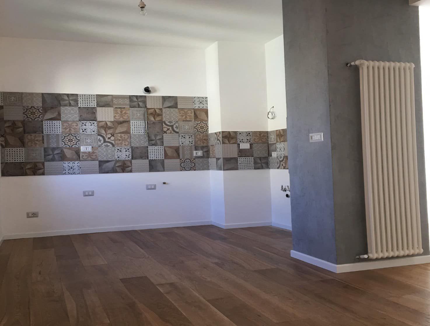 Una stanza vuota con un termosifone e piastrelle sul muro