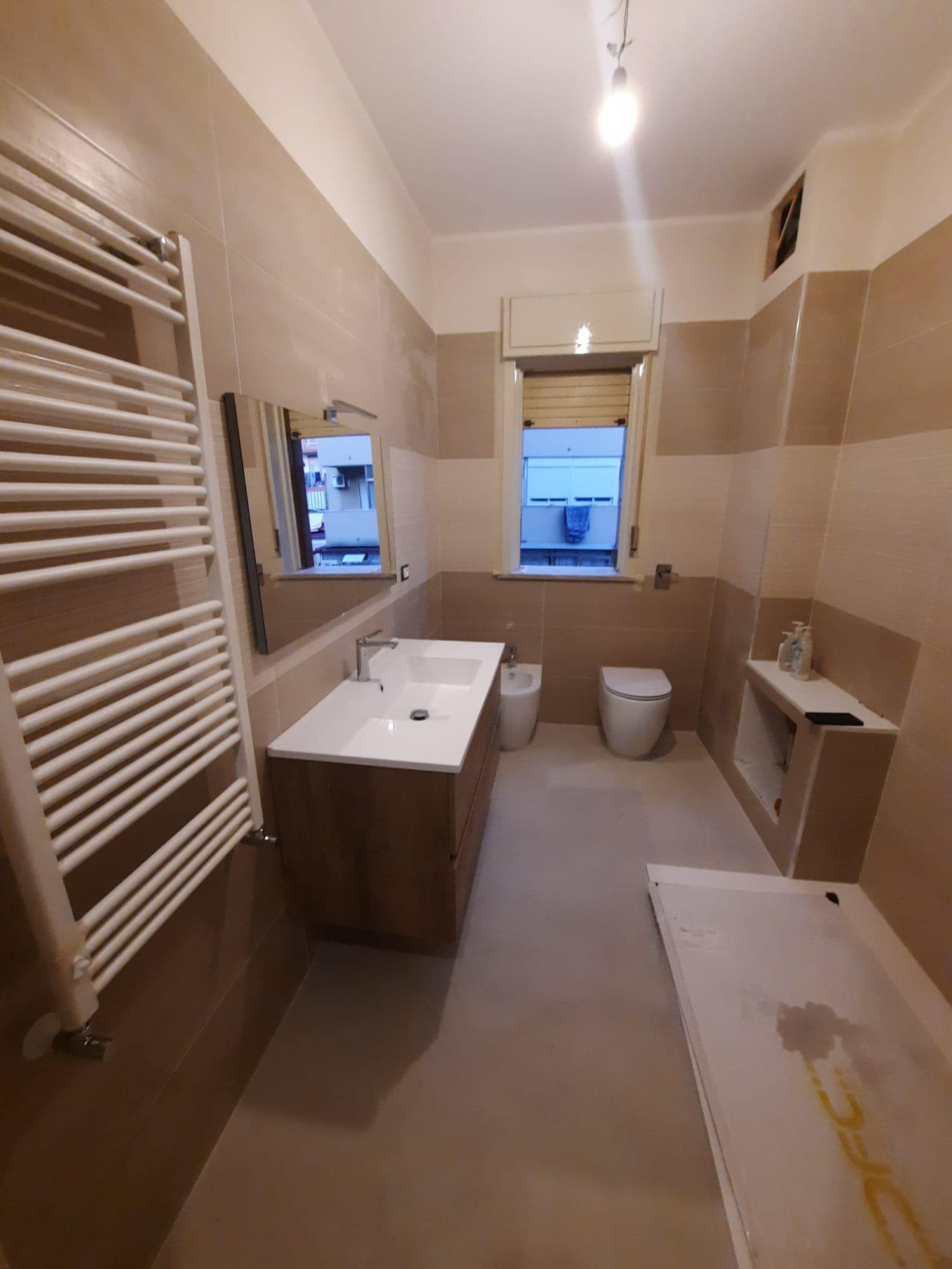 Un bagno con lavandino, water, specchio e portasciugamani.